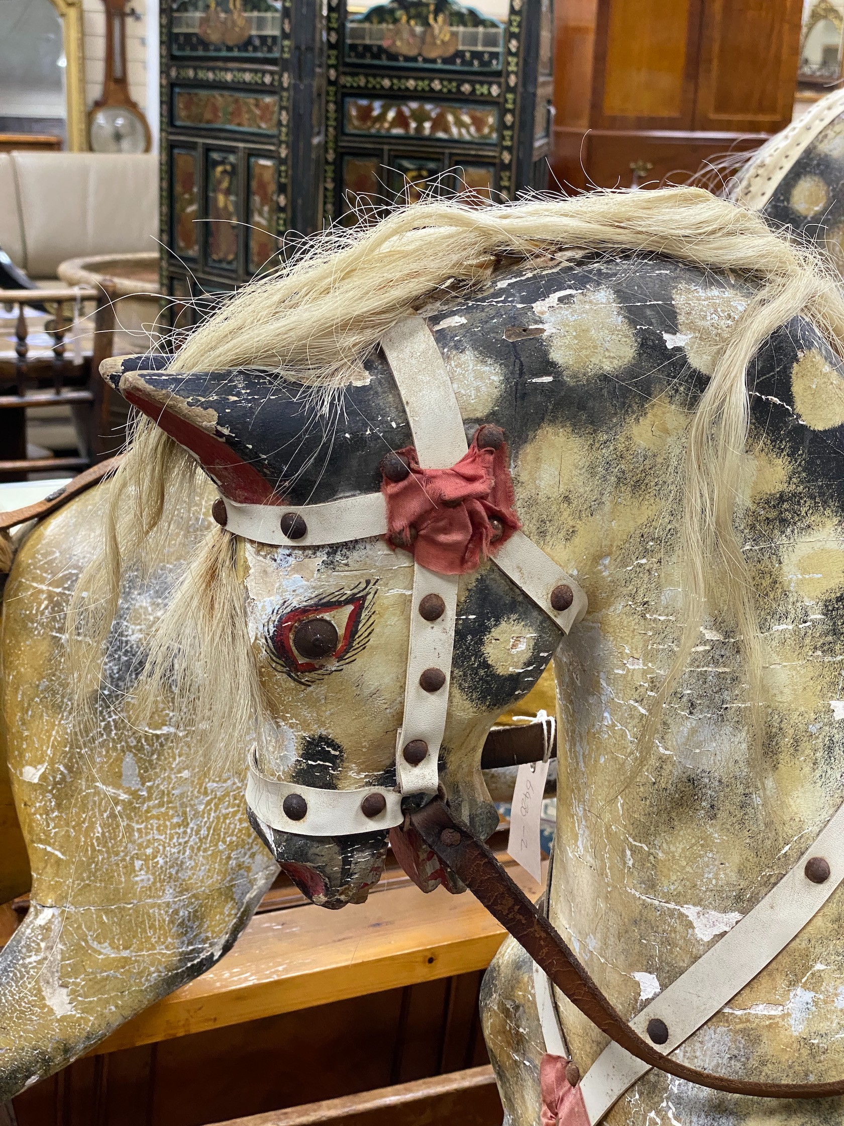 An early 20th century Ayres type carved wood and dappled rocking horse on safety frame, length 138cm, height 116cm